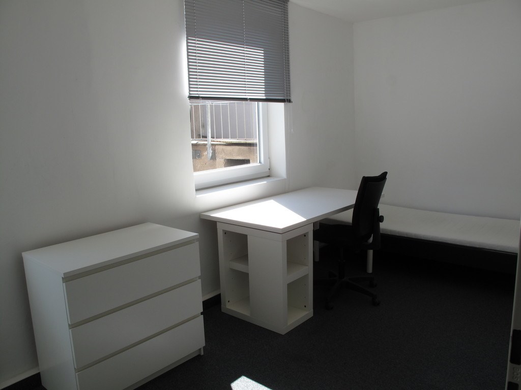 Helles Zimmer mit Schreibtisch und Bett